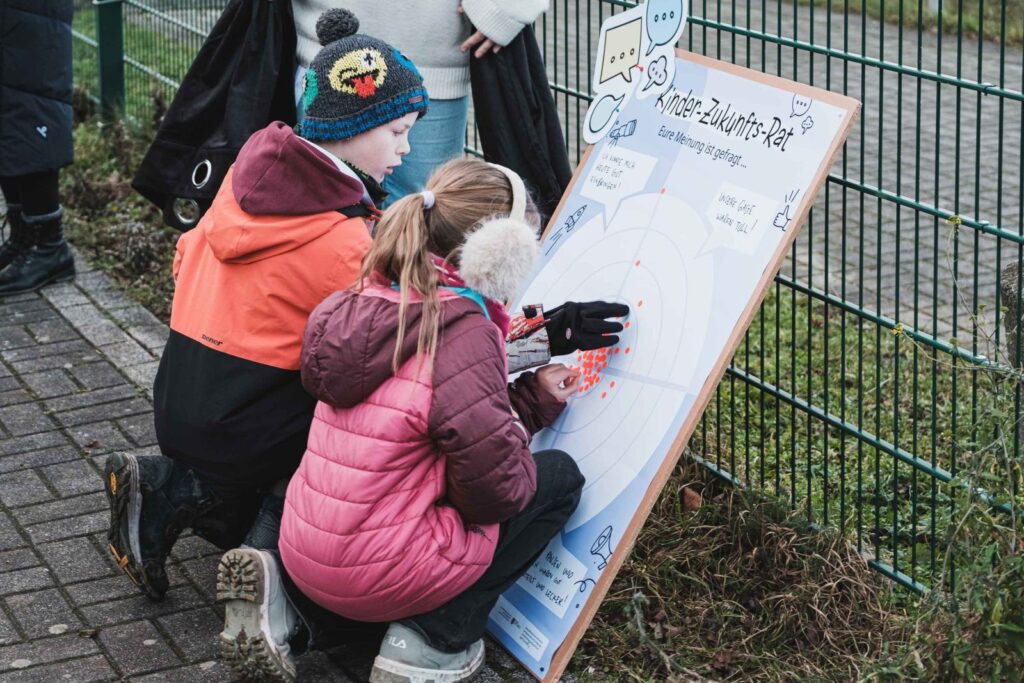 Zwei Kinder notieren auf einem großen Flipchart ihre Analyse zu einer Sportstätte im Rahmen des "Kinder-Zukunfts-Rates" in Moritzburg .